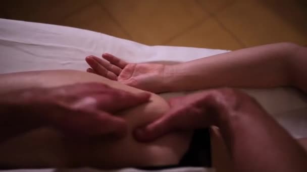 Masér masíruje dívky zadek nohy s rukama pod romantickým nízkým světlem — Stock video