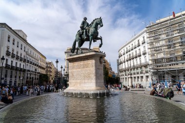 Madrid, İspanya. 19 Eylül 2025. Güneşli bir günde etrafa dağılmış bulutlar ve turistlerle birlikte Puerta del Sol Madrid 'de V. Felipe' nin oğlu Kral III. Carlos 'un atlı heykelinin editör fotoğrafı..