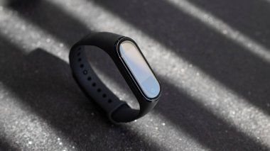 Siyah arka planda siyah elektronik saat ve akıllı fitness takip cihazı. Karanlık arka planda karanlık bir nesne. Karanlık lüks bir ruh hali. moda aksesuar sporu