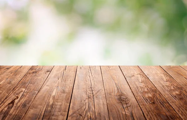 Empty wooden brown tabletop with a blurry, defocused garden. Summer is spring. For installation of a product display or visual design of a key, environmental product advertising template. Copy space