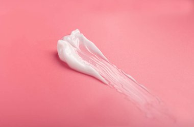Kozmetik nemlendirici krem lekesi. Pembe arka planda, fotokopi alanı ile izole edilmiş. Yüz ve vücut bakımı kavramı.