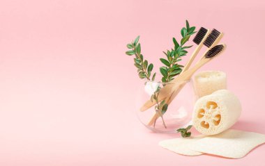 Üç bambu, pembe arka planda cam bir fincanda ahşap fırçalar. Banyo lifleri. Uzayı kopyala Tıp kavramı, sıfır atık, geri dönüşüm.