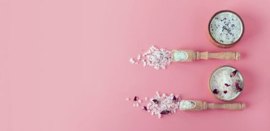 İki tip Himalaya banyosu ve spa eko tuzu. Spa tedavisi. Rahatlama endüstrisi. Ahşap bir tabakta banyo kristalleri. Fotokopi alanı Afişi olan pembe bir arka planda yatıyordu. Gül, lavanta