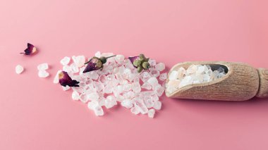 Spa ve banyo için tuz kristalleri, fotokopi alanı olan pembe bir zemine saçılmıştır. Gül yaprakları ve tomurcukları ile temel yağ. Alternatif tıp konsepti, rahatlama, nefes alma. Eko