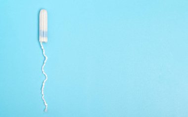 Mavi arka planda tek kullanımlık adet tamponu. Adet döngüsü. Hijyen ve koruma. Adet, kritik günler, adet döngüsü, kadın sağlık konsepti.