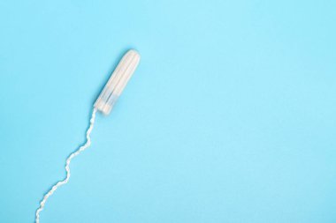 Mavi arka planda tek kullanımlık adet tamponu. Adet döngüsü. Hijyen ve koruma. Adet, kritik günler, adet döngüsü, kadın sağlık konsepti.