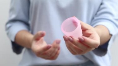 Adet bardağının nasıl kullanılacağını. Kadın, tıbbi silikondan yapılmış regl eko bardağının nasıl çöktüğünü gösteriyor. Video talimatı. Yakın plan, sıfır atık, çevre dostu konsept