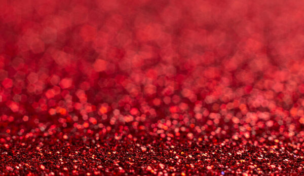 Red festive Christmas background. Abstract shimmering bright background with bokeh defocused red lights. Shiny gradient with copy space. Ruby wedding, new year, valentine's day concept. Glitter.