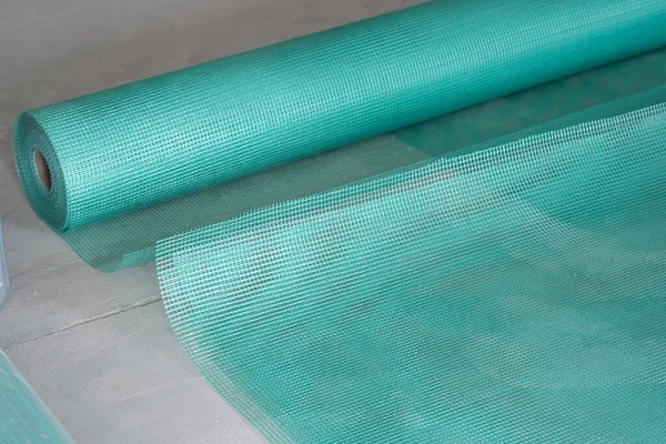 Close-up of green blue reinforcing mesh rolled up. A building resource for reinforcing walls in the process of insulating or leveling them. Plastic mesh for plastering. Home renovation.