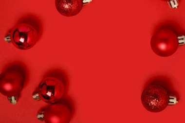 Kırmızı arka planda fotokopi alanı ile süslenmiş Noel süsleri. Yeni yıl. Asgari düzeyde. Düz yatıyordu. Dinamik kutlama kompozisyonu.