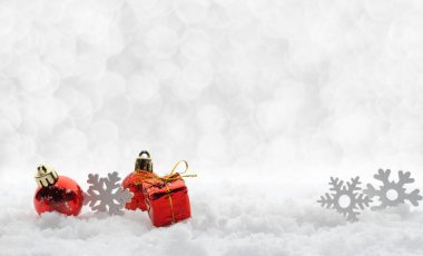 Güzel kırmızı ve beyaz Noel süsleme oyuncakları kar taneleri ve toplar, arka planda kar olan hediye kutusu ve fotokopi alanı olan açık gümüş bokeh. Yeni yıl, Mutlu Noeller greiting kartı.