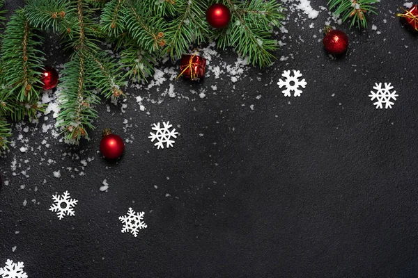 Noel ya da Yeni Yıl dekorasyon geçmişi. Köknar ağacı dalları için fotokopi alanı olan siyah arkaplan. Düz yatıyordu. Şablon. Beyaz kar taneleri ve kar, kırmızı toplar.