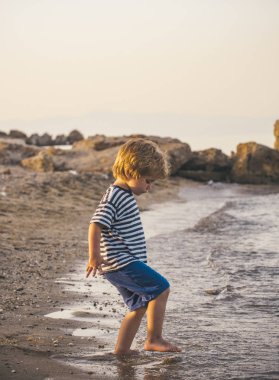Çocuk deniz kenarında yürüyüş, çocuk sahilde su ile oynuyor. Gelgit Okyanusu, bir yaz yürüyüş. Çocuk ve doğa, deniz kıyısında, yaz, turizm, tatil çocuk ile. Kıyı üzerinde yalnız çocuk