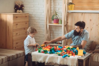 Baba ve oğul plastik bir tasarımcı ile oynuyorlar. Ailenizle evde, renkli arka plan. Sakallı bir adam, iyi bir baba, ihale duyguları, Oyunlar ailesi ile. Küçük bir oğlun babası ile oynanır