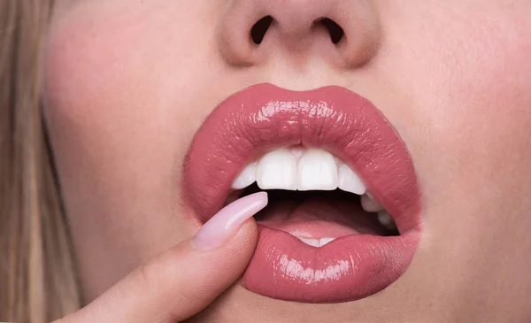Open female mouth with pink lipstick. White teeth of beautiful young women. Seductive lady mouth and nude lips close up. Sexy natural nude lips. Glamour, sensual, nude make up for ladies. Stomatology