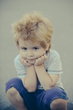 Sevimli küçük çocuk kameraya bak ve oturur. Hayal kırıklığına uğramış çocuk aile yürüyüş. Kaprisli çocuk ve psikologlar. Üzgün çocuk onun çene altında onun elini tut. Yalnız, unsoicable çocuk. Çocuk portre