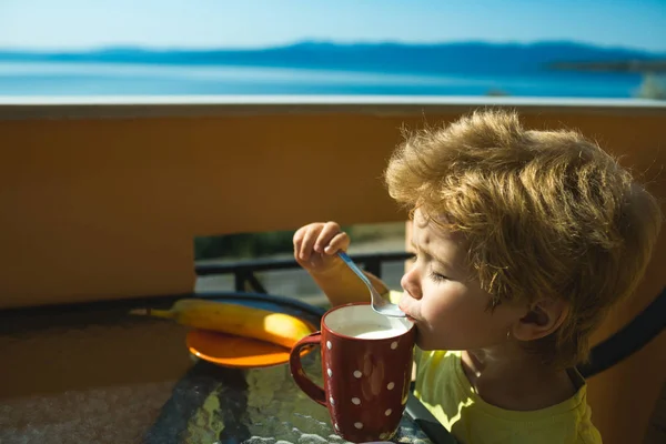 子供は 牛乳を飲みます 汚い口でおいしく健康な牛乳 朝の朝食のための高速炭水化物 子供のためのバランスの取れた食事 ギリシャの海に近い一緒に海辺の家族安静時朝 — ストック写真