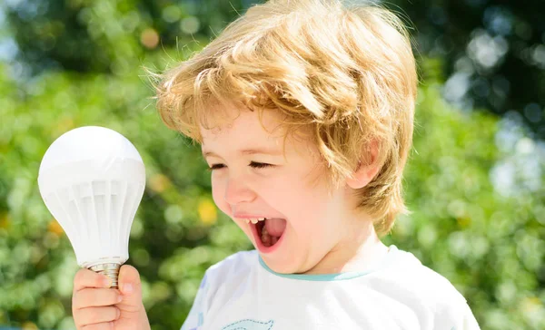 成功のアイデア 子供は電球によって楽しんだ 光と電気 エネルギー ポジティブなエネルギー 笑いと幸福 美しい少年は 彼の手と笑いで電球を保持します 楽しく — ストック写真