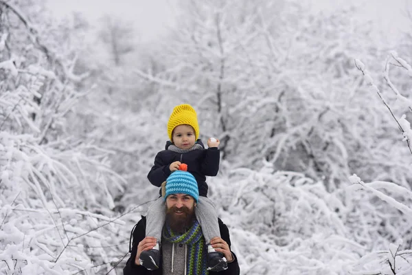 Snowballs. Game with father. Outdoor walk of happy father and son smiling. Young man and little boy, snowball in child hand and enjoying to winter walk together. December holidays. Merry Christmas