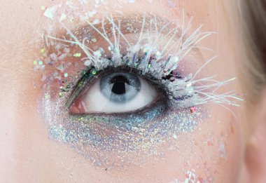Ayaz profesyonel kış moda fotoğraf oturumu için telafi. Beyaz maskara ve kirpik üzerinde sparckles. Kar kraliçesi soğuk makyaj ile genç kadının mavi göz. Kadın göz makyaj ile yakın çekim