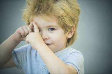 Eğlenceli eller gri arka plan üzerinde izole jest, çocuk yapar. Sevimli sarışın yürümeye başlayan çocuk elleri ve gülümsüyor için kamera ile oynuyor. Kurnaz küçük çocuk. Çocuğun zeki bak akıllı. Komik çocuk 3 yaşında portre