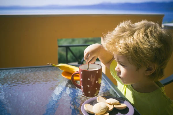 Morgenmad Koncentreret Blond Barn Sætter Ske Kop Med Mælk Banan - Stock-foto