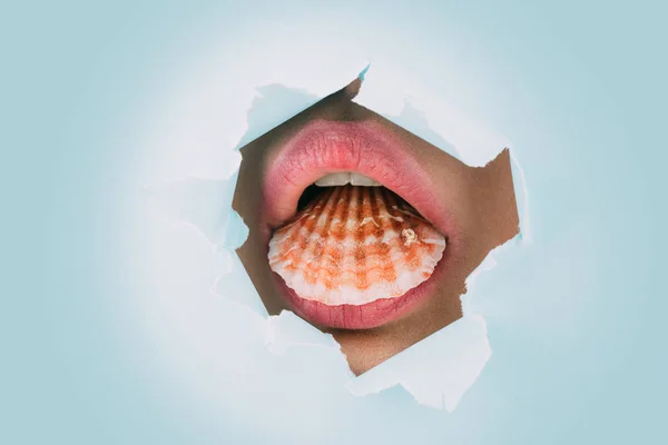 Shell in the female mouth. Marine sea concept. The lips of the girl in the paper hole. Oral caress. Sea tourism. Ocean theme. Nautral face makeup. Sea minerals for health. Healthy teeth, calcium