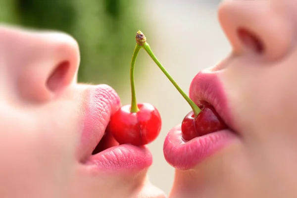 Lesbian couple kiss lips. Sexy lesbian lovers foreplay. Cherry and temptation. Two fruits for two women. Female mouths together close-up