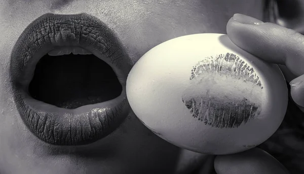 Easter kiss. Woman open mouth with egg. Symbol of love and life. Happy Easter. Imprint lipstick, sensual concept. Feminine and woman energy. Lips of girl with make up