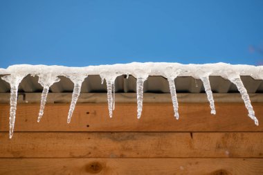 Kışın Amerika Birleşik Devletleri'nde binasında buz sarkıtları. Soğuk bir bulutlu gün şehir dışında bir ahşap evin çatısı buz sarkıtları asmak