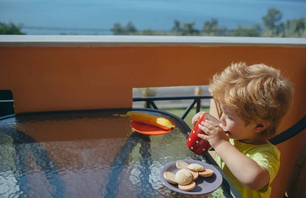 Petit déjeuner savoureux et garçon buvant du lait. Énergie du matin provenant de la nourriture. Banane, lait et biscuits et glucides rapides. Aliments sains pour les enfants. Régime sans gluten et sans lactose. Déjeuner sur la terrasse . — Photo