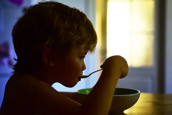 離乳食。子供が皿から食べる。ディナー。こどもの食べ物。かわいい美少年を食欲で食べる。キッチンやお子様、ダイエット用のメニュー. — ストック写真