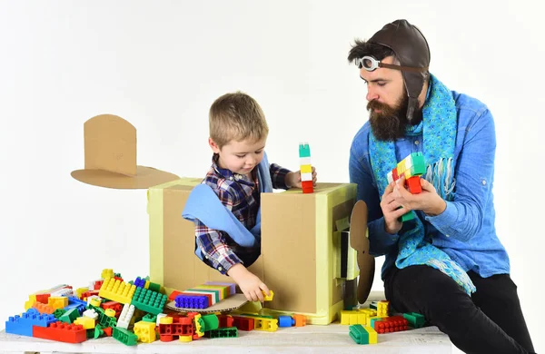 Child and father construct small planes from cubes. Developing games for children. Young pilot sits in cardboard plane and play with cubes with adult. Family time. Activities for the youngest