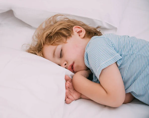 Cute sleeping baby boy. A child in a dream. Phases of sleep. Deep dream. Daily regime. Child development and health. Bed and bedding. Favorite pillow.