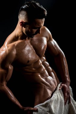 Atletik genç adam havlu onun beline giyiyor ve siyah arka plan üzerinde duruyor. Banyo sonra genç vücut geliştirmeci şehvetli portresi. Mens sağlık ve seksi kas vücut kavramı.