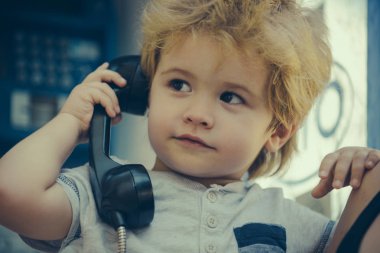 Telefon. Bir çocuk bir vintage telefonla konuşuyor. İletişim. Çocuk ile konuşma. Yetiştirme.