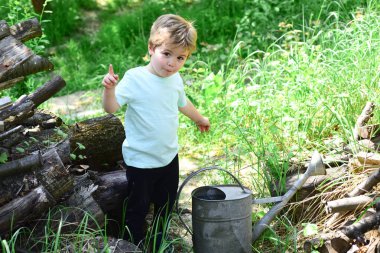 Güzel bir çocuk hakkında bir şey bilmiyor. Büyük sulama pot önünde çim çevrili küçük çocuk var. Genç çocuk Çim Sulama pot kullanma su istiyor. Köydeki çocuklar için etkinlikler