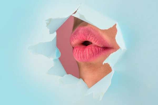 Bela gordura lábios brilhantes de cor rosa espreitar na fenda de papel colorido. Maquiagem, maquiagem, publicidade, facial, boutique, pele lisa, emoções, surpresa. Valentine beijo . — Fotografia de Stock