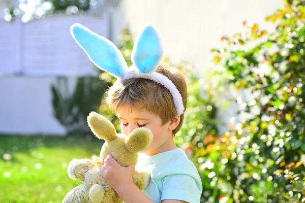 Osterjunge mit Spielzeug. süßes Kind Baby umarmt einen Teddybär. Der Junge trägt Hasenohren für den Urlaub. — Stockfoto