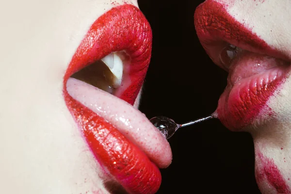 Lesbian kiss, saliva between two female tongues in the mouth. Girls with red lipstick kiss. Sex and passion isolated on a black background, white skin, tender feelings, seductive sensual kiss — Stock Photo, Image