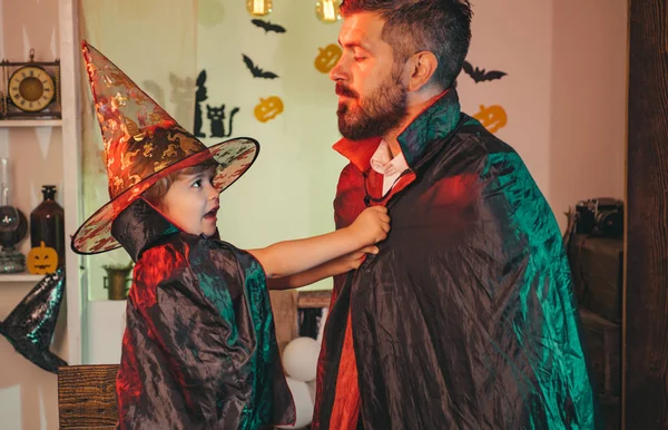 Wizard party. Boy puts a superhero overcoat on a bearded man. Father and son play together in a fabulous wizard. Funny masquerade weekend. Costume Party.