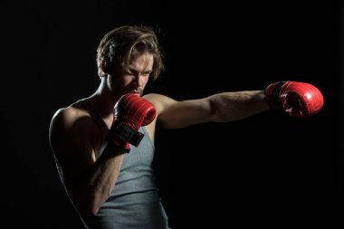 Kırmızı eldiven ve gri gömlek boksör. Boksörü, darbe, darbe. Karanlıkta çekici kick boks portresi. Genç adam egzersiz spor salonunda boks,