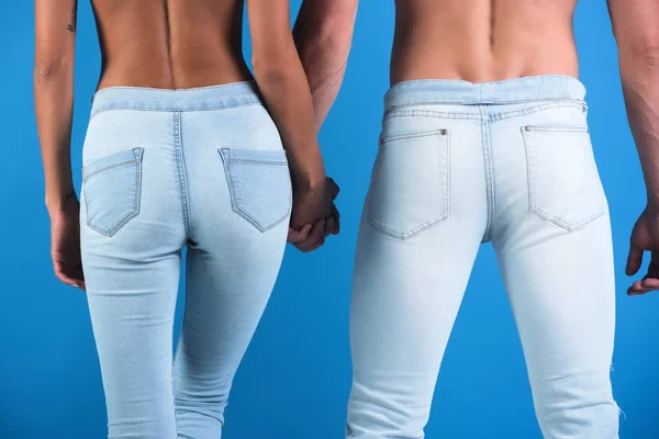 Los vaqueros seductores de la pareja que usan que acentúan la forma hermosa. El hombre sostiene a una mujer a mano, ternura y armonía en la relación. Culo y nalgas de pareja enamorada. Sexy espalda desnuda, pantalones vaqueros —  Fotos de Stock