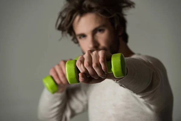 Man with sport dumbbells. Joy sport. Handsome guy holding green dumbbells in hands. Beautiful fingers of man. Morning exercises for energy and successful day. Bearded stylish guy with long hair
