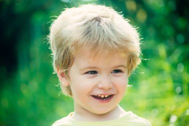Sevimli genç mutlu çocuk. Çocuk portre, yeşil doğa zemin üzerine gülen surat. Güzel bebek yüz, mutlu çocukluk, gülümseyen, çocuk smile diş ile. Mutlu neşeli güzel bir çocuk