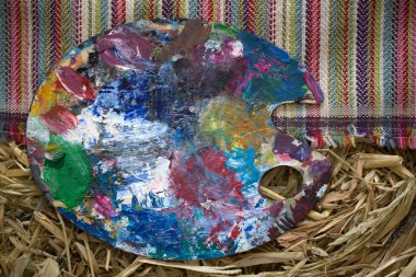 Palet resim çizmek için boyar. Sanatçılar paleti, yakın çekim. Parlak yağlı-boya paleti closeup arka plan görüntüsü. Renk paleti, saman arka plan ve el yapımı halı boyama