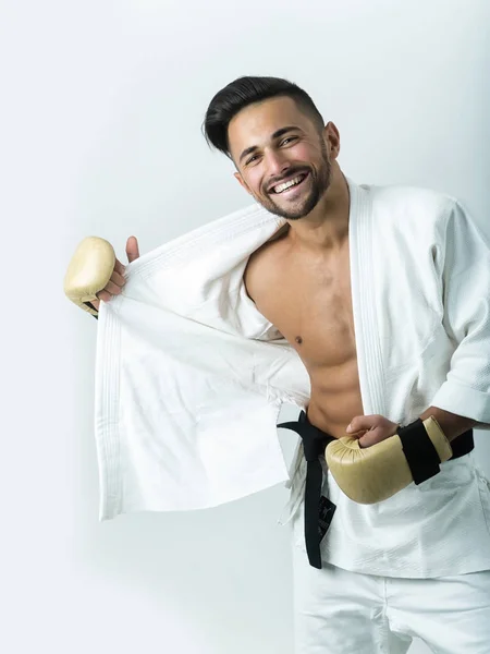 Alegre atleta barbudo se quita el kimono. Felicidad en la cara de luchador. Amplia sonrisa chico cuerpo guapo. Explosión de emociones positivas durante una sesión fotográfica. atleta feliz abre desnudo pecho — Foto de Stock