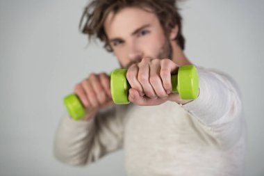 Spor egzersiz eğitmen kavramı. Genç adam sabah egzersizleri yapar. Beyaz kazak, genç yenilikçi, güçlü ve şık bir adam sakallı adam sağlıklı yaşam tarzı olur. Eğitim için yeşil küçük halter