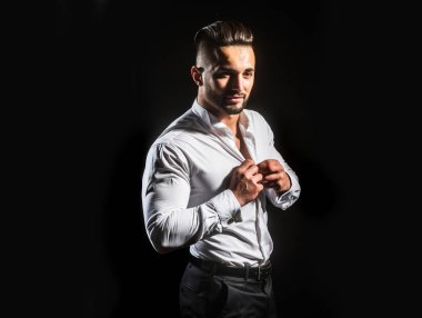 Beyaz bir gömlek düğmeleri. Onun beyaz gömlek ayakta siyah arka plan üzerine kadar adam düğmeleri. İşadamı sabah iş hakkında düşünüyor. Giyim erkek, klasik beyaz gömlek ve pantolon için