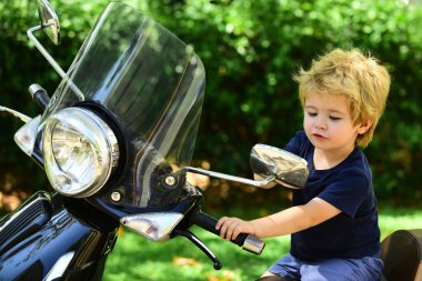 Şirin çocuk sürme motosiklet yalnız çalışır. Neşeli mutlu samimi duygular üzerinde temiz hava. Duygusal çocuk motosiklet üzerinde oturur ve düşmemek için motosiklet üzerindeki tutar. Dikkatli sürücüleri.